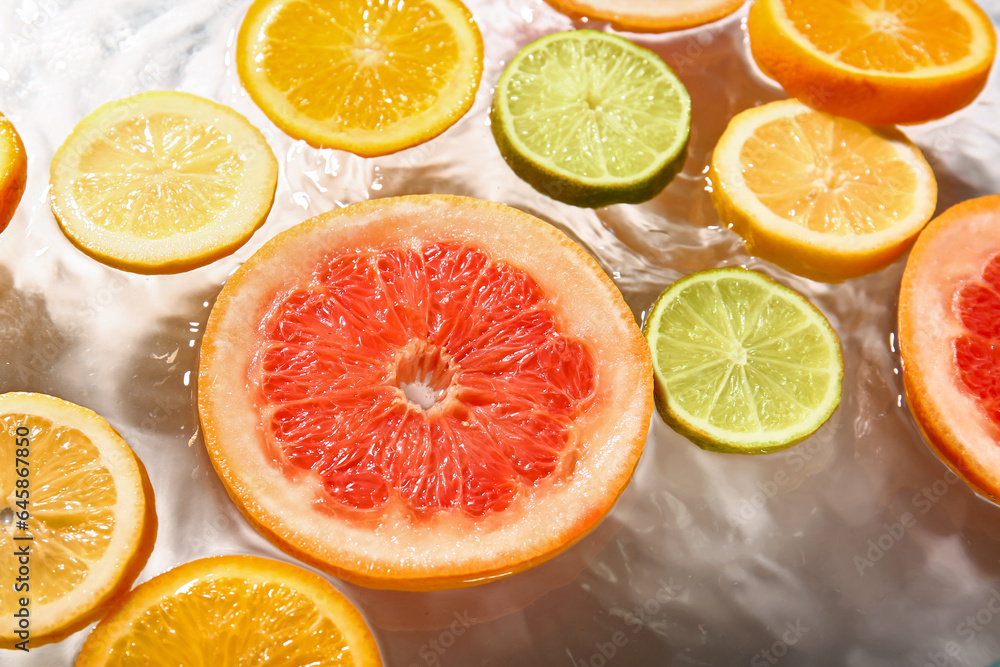 Different citrus fruit slices in water on white background Different citrus fruit slices in water on white background