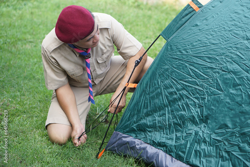 Φωτογραφία Thai boy scout is setting up the tent at campsite for camping outdoor