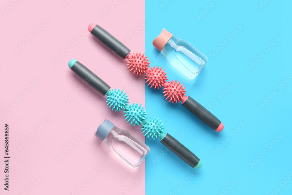 Body rollers and bottles of water on color background