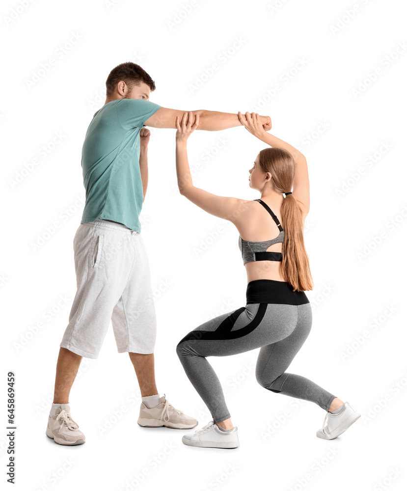 Young woman fighting with instructor of self-defence course on white background