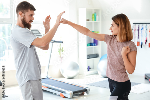 Canvas-taulu Instructor teaching young woman to fight in gym