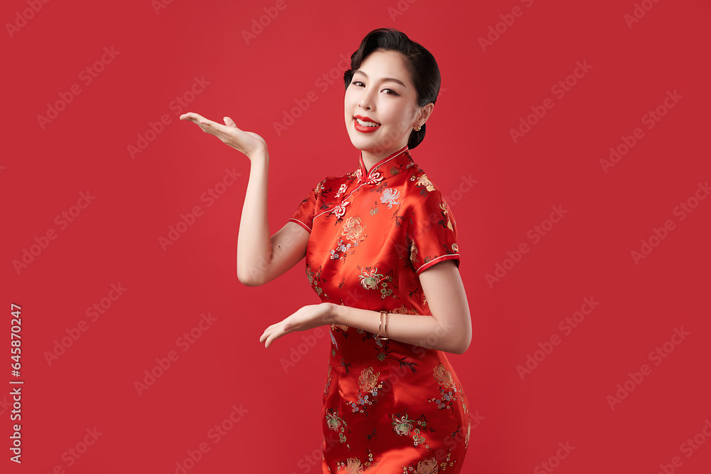Asian woman wearing traditional cheongsam qipao dress with gesture of introduce isolated on red background, Happy Chinese new year. Asian woman wearing traditional cheongsam qipao dress with gesture of introduce isolated on red background, Happy Chinese new year.