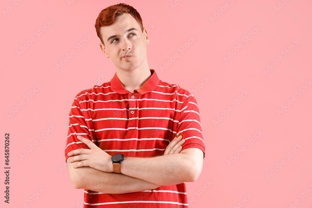 Thoughtful young redhead man with wrist watch on pink background Thoughtful young redhead man with wrist watch on pink background
