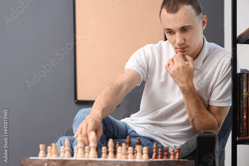 Young man playing chess at ...