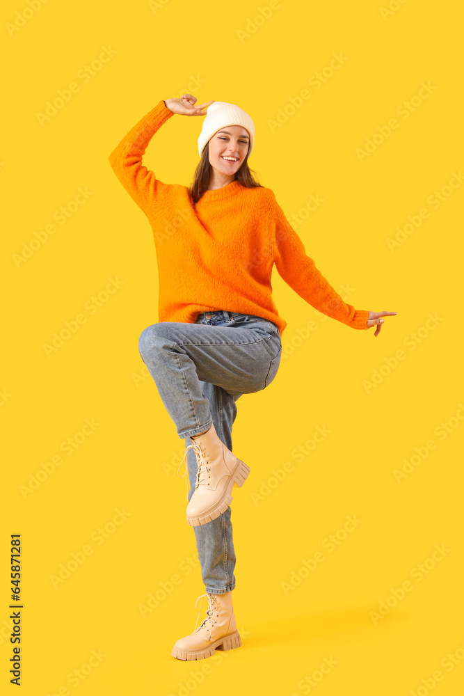 Happy young woman in winter clothes on yellow background Happy young woman in winter clothes on yellow background