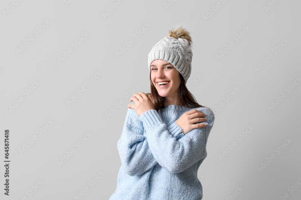 Young woman in winter clothes on light background Young woman in winter clothes on light background