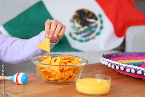 Young Mexican woman eating nachos at home  closeup
