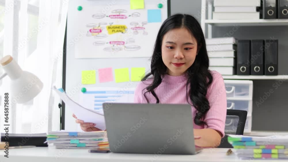 Asian woman working on paperwork with laptop on desk in office. Asian woman working on paperwork with laptop on desk in office.