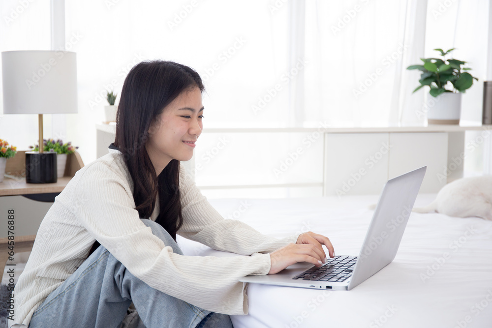 Beautiful young asian woman smile sitting working on laptop computer to internet online with cozy with companion dog in the bedroom at home, woman using notebook leisure with pet, lifestyles concept. Beautiful young asian woman smile sitting working on laptop computer to internet online with cozy with companion dog in the bedroom at home, woman using notebook leisure with pet, lifestyles concept.