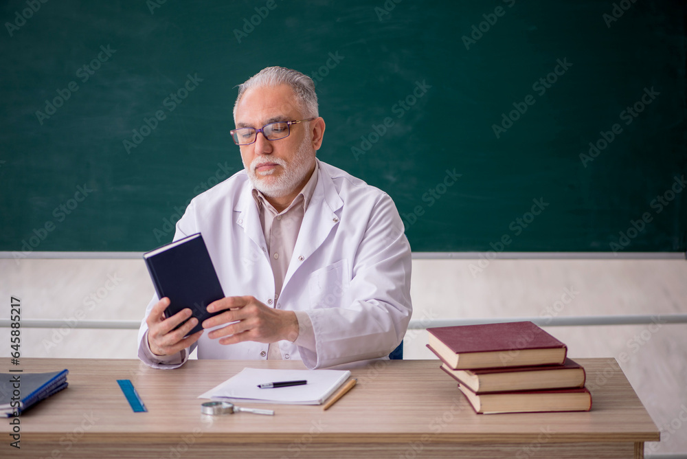 Old male teacher in front of green board Old male teacher in front of green board