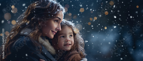 A young girl with mom watches in wonder at the first snowfall of the season.