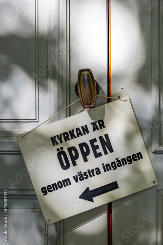 Photography Stockholm, Sweden A sign on the door of the Adolf Frederik Church in downtown says in Swedish to  English translation: Church is open by the western entrance