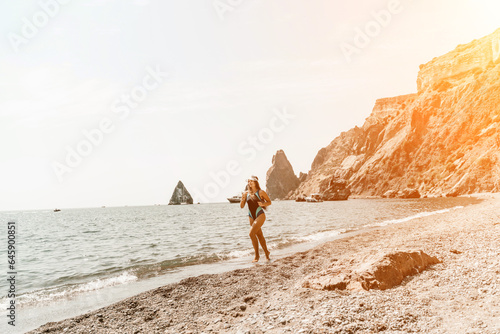 Woman travel summer sea. A happy tourist in a blue bikini enjoying the scenic view of the sea and volcanic mountains while taking pictures to capture the memories of her travel adventure.