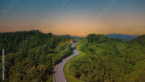 The sunset view with  highway stairs to the sky of road trough with green forest  as the nature landscape background