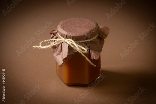 Caramel in a  glass jar, brown background