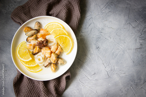 Seafood with fresh  lemons-shrimps, mussels, squid, baby octopus, white plate, gray background. Seafood board, healthy eating , mediterrian , italy food, seafood diet photo