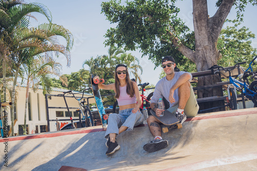 Young happy couple with skateboards enjoy longboarding at the skatepark