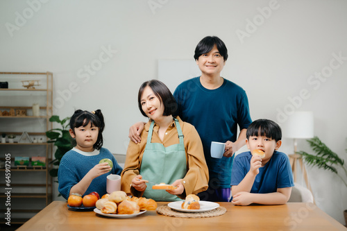 Happy asian family father and mother little toddler asian boy daughter child having fun cooking together with dough bake cookie and cake ingredient on table .