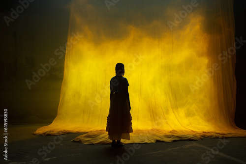 Silhouette of a Woman in a Dark Setting With a Yellow Curtain Backdrop