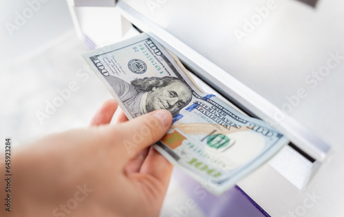 Young woman holding money in her hands after withdrawing the cash at the ATM