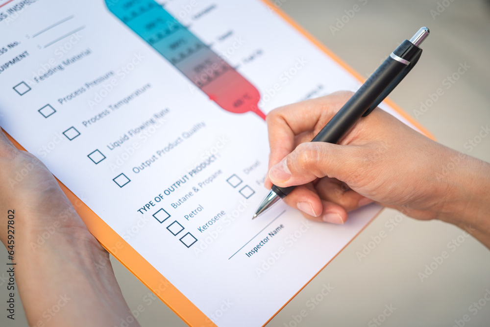 Action of a chemical engineer is using the pen to checking on oil refinery distillation process inspection form. Industrial working scene,close-up and selective focus. Action of a chemical engineer is using the pen to checking on oil refinery distillation process inspection form. Industrial working scene,close-up and selective focus.