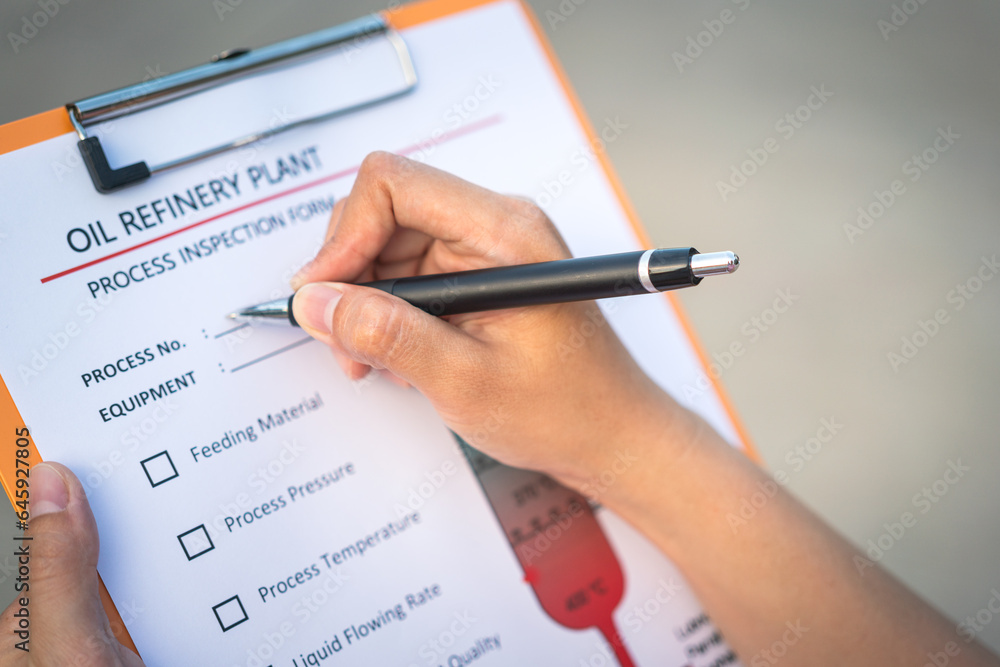 Action of a chemical engineer is using the pen to checking on oil refinery distillation process inspection form. Industrial working scene,close-up and selective focus. Action of a chemical engineer is using the pen to checking on oil refinery distillation process inspection form. Industrial working scene,close-up and selective focus.