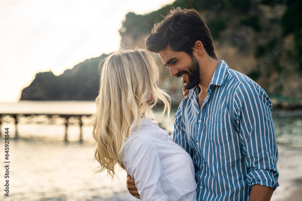 Charming young couple bonding at the beach in summer. Romantic male and female looking each other into each other's eyes during the sunset. Charming young couple bonding at the beach in summer. Romantic male and female looking each other into each other's eyes during the sunset.