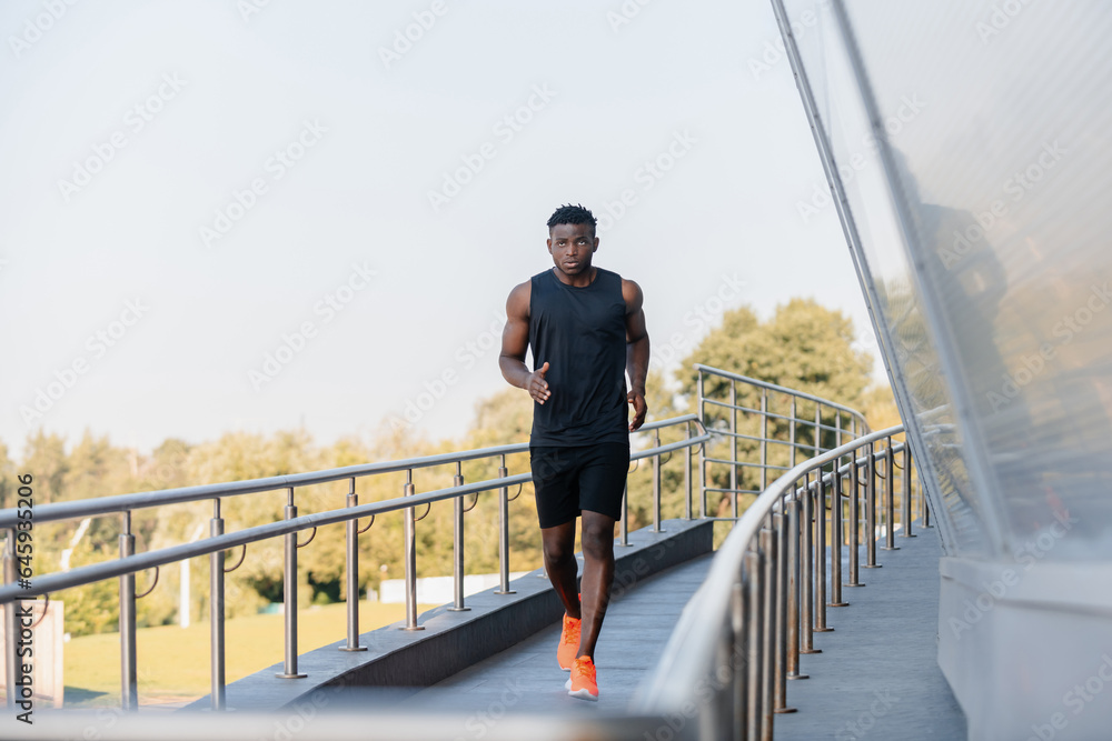 Full length of active African athlete in sportswear looking concentrated while running outdoors