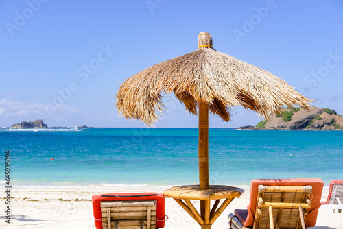 Umbrellas made from palm leaves and wood and sun shade ropes provide a shady getaway on Lombok Beach,  palm leaves umbrella and chairs at Lombok, lounge chairs on the beach, Tanjung Aan Beach Lombok photo