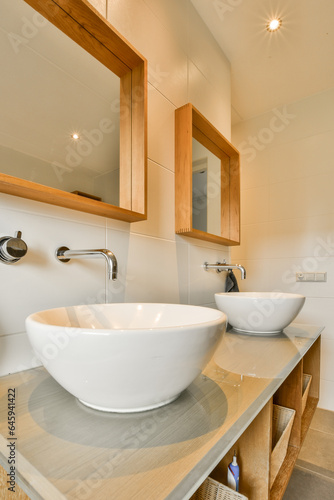 a modern bathroom with two sinks and mirror above the sink is in focus to the light coming through the window