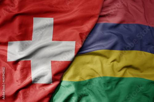 big waving national colorful flag of switzerland and national flag of mauritius .