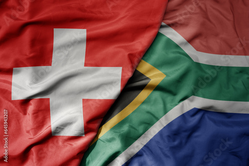 big waving national colorful flag of switzerland and national flag of south africa .