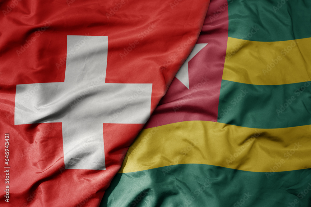big waving national colorful flag of switzerland and national flag of togo . big waving national colorful flag of switzerland and national flag of togo .