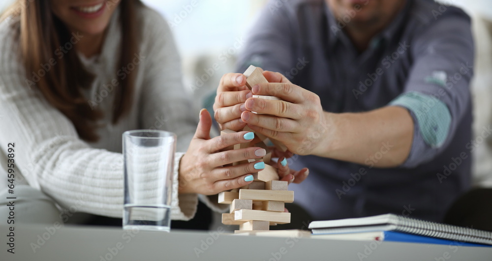 Obraz premium Focus on wooden tabletop board game. Worried people spending quality time with close friend or relative. Warm lovely evening concept. Blurred background
