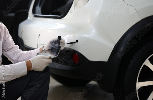 Fototapeta Naklejka Na Ścianę i Meble -  Close-up of male automechanic hands holding modern digital tablet and car tube in white gloves and working. Smart mechanic at service station. Automotive check concept. Copy space on screen