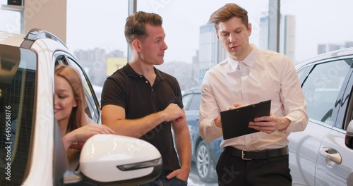 pensive puzzled man listening to salesman very attentively, shop assistant holding a folder, trying to sell bad car, fraudsters working in showroom, fake documents in dealership Crime Slow motion
