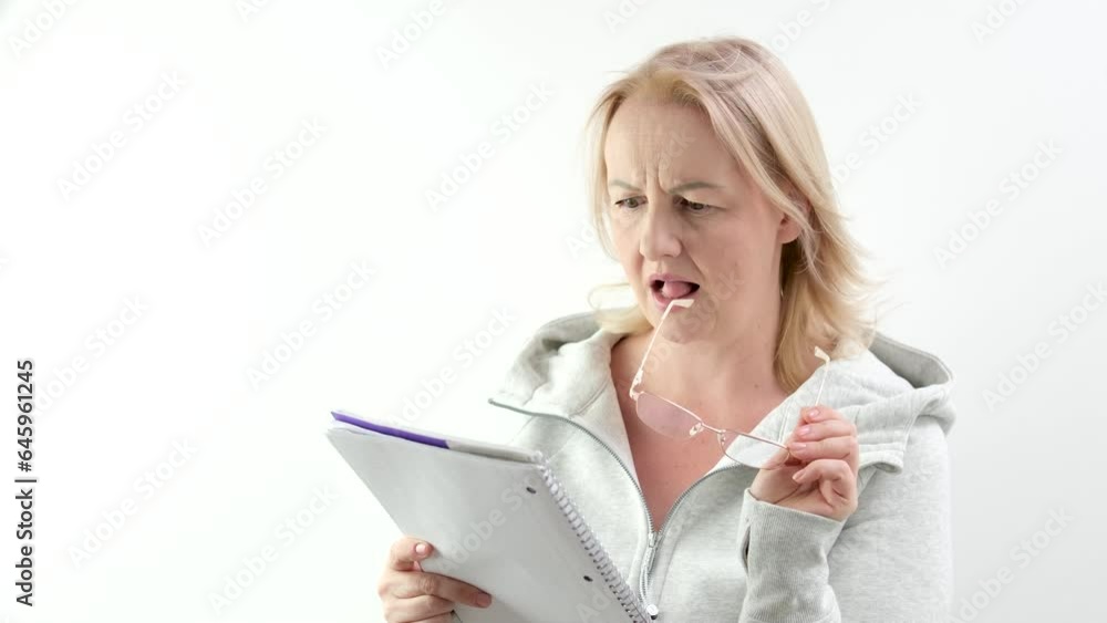 adult woman is reading, thinking about something, biting glasses with teeth, unpleasant facial expression, dissatisfaction, solving problem, not understanding what is written, eyesight has fallen adult woman is reading, thinking about something, biting glasses with teeth, unpleasant facial expression, dissatisfaction, solving problem, not understanding what is written, eyesight has fallen