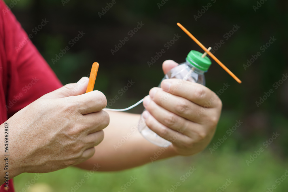 Foto de Close up hands hold DIY toy made from plastic bottle, rope and ...