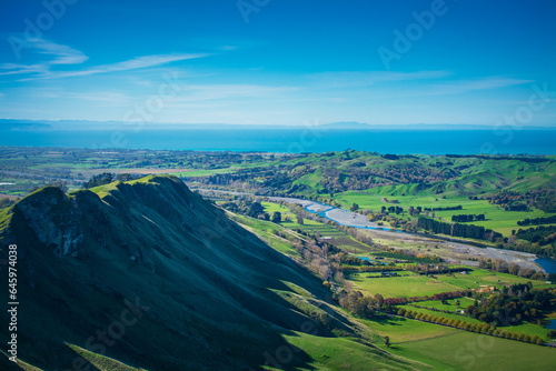 The light and shade on the lush green slopes of Te Mata Peak. Tukituki River flowing towards sea. Gorgeous autumn day in Hawkes Bay, New Zealand photo