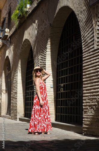 Young and beautiful blonde woman with sunglasses and straw hat on her head walking in the historical centre of seville. The woman is on holiday and enjoys the city. The woman is happy. © @skuder_photographer