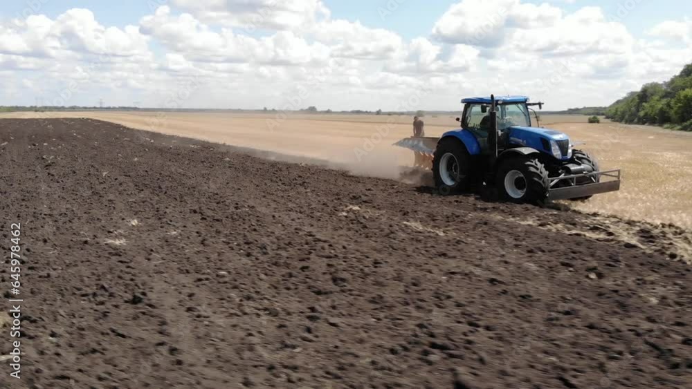 Blue tractor plowing the field after wheat in Ukraine Blue tractor plowing the field after wheat in Ukraine