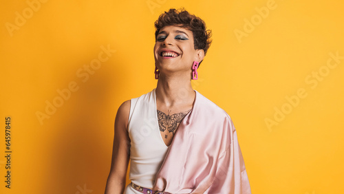 Transgender person laughing while looking at camera on a yellow background