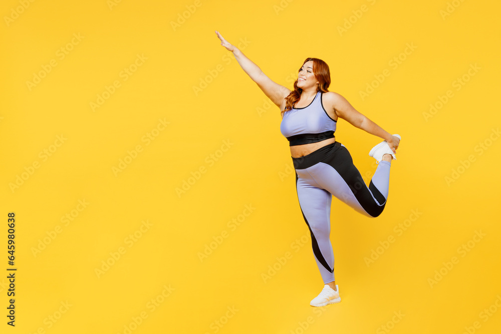Full body side view young chubby plus size big fat fit woman wear blue top warm up train do stretch exercise for hand and leg isolated on plain yellow background studio home gym Workout sport concept
