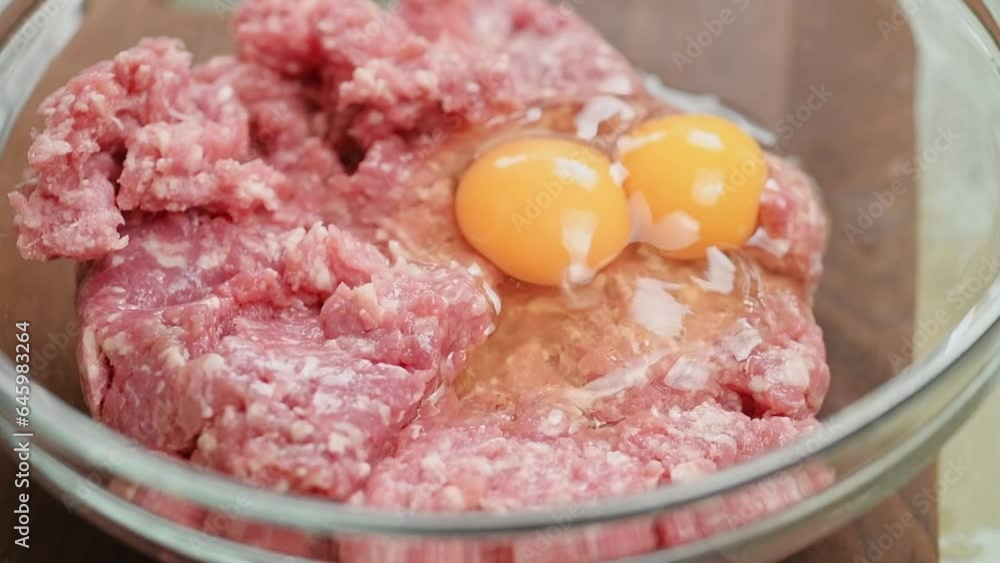 The cook adds egg to the minced meat in a glass bowl.
The cook adds egg to the minced meat in a glass bowl.