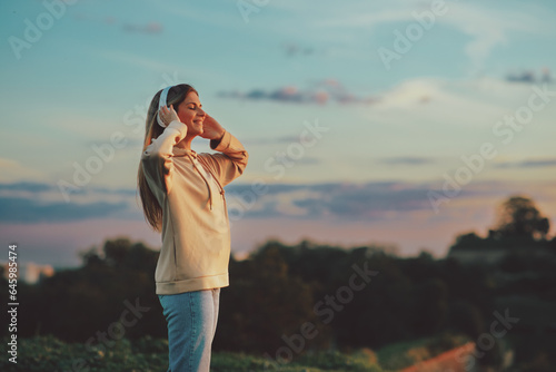 Wallpaper Mural Young woman watching the sunset while listening to music via headphones Torontodigital.ca