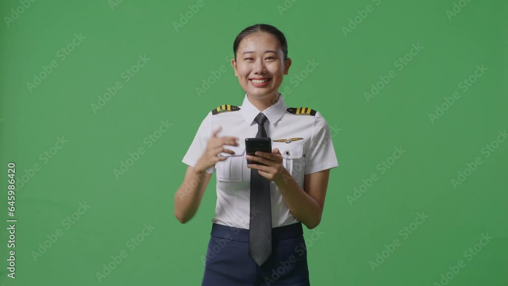 Asian Woman Pilot Smiling And Pointing To Smartphone In Her Hand While Standing In The Green Screen Background Studio
Asian Woman Pilot Smiling And Pointing To Smartphone In Her Hand While Standing In The Green Screen Background Studio