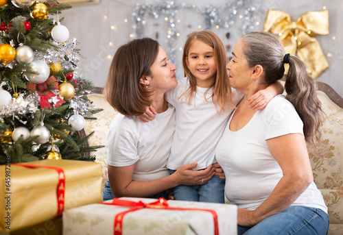 Portrait of grandmother, mother and girl at Christmas on sofa bonding, loving and enjoying holiday season