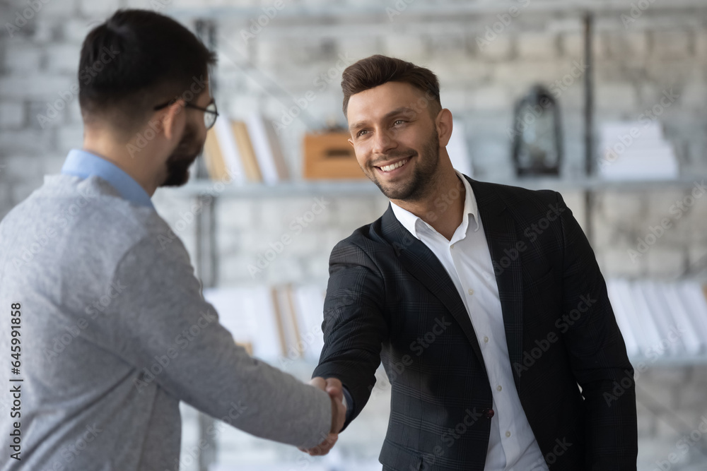 Smiling young businessmen shake hands get acquainted greeting at office meeting, happy motivated male business partners handshake closing dal or making agreement at briefing, partnership concept Smiling young businessmen shake hands get acquainted greeting at office meeting, happy motivated male business partners handshake closing dal or making agreement at briefing, partnership concept