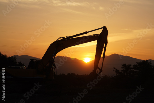 silhouette of excavator machine with sunset photo