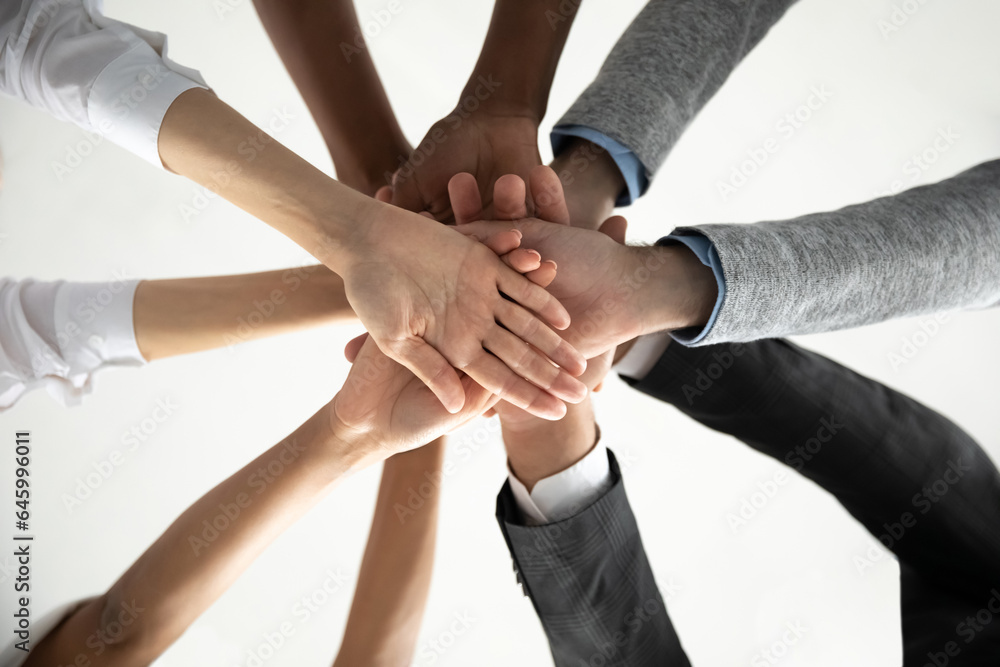 Close up view from below of multiethnic diverse colleagues join stack hands in pile show unity and strength at work, multiracial coworkers engaged in teambuilding activity, motivated for shared result Close up view from below of multiethnic diverse colleagues join stack hands in pile show unity and strength at work, multiracial coworkers engaged in teambuilding activity, motivated for shared result
